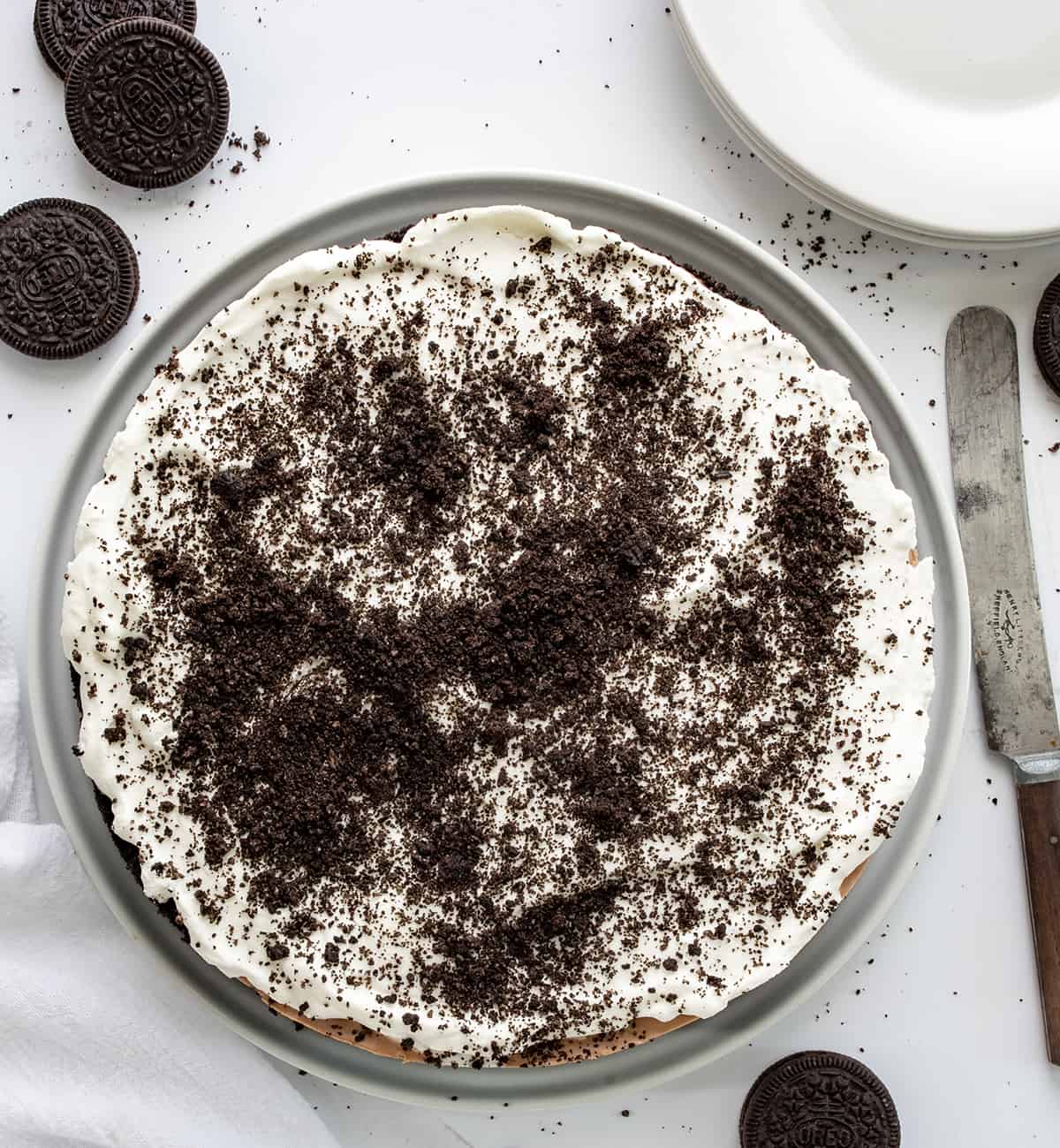 Overhead of a Triple Chocolate Mousse Pie on a White Counter with Oreos and Plates.