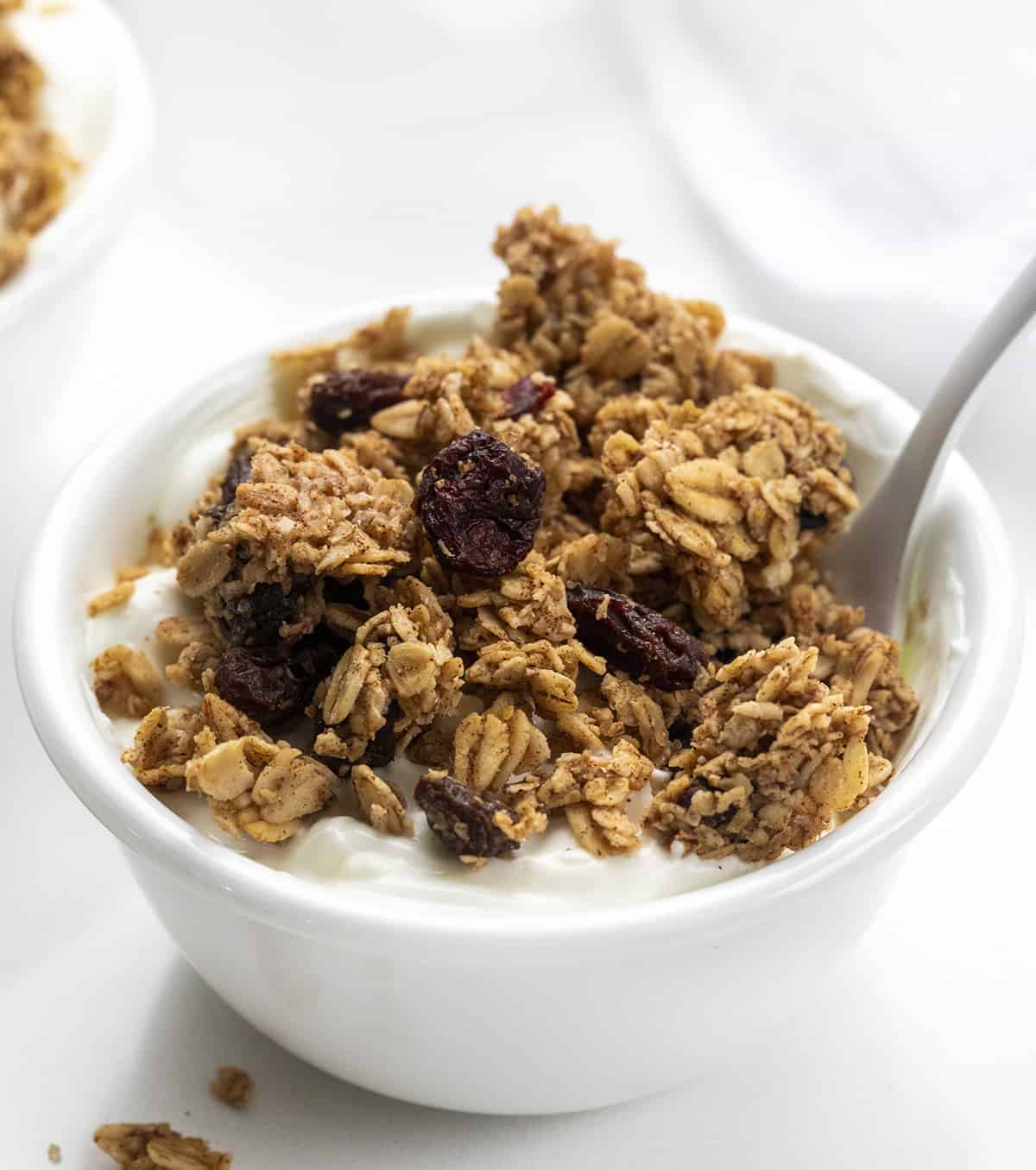 Bowl of Yogurt with Homemade Granola in it and a White Spoon