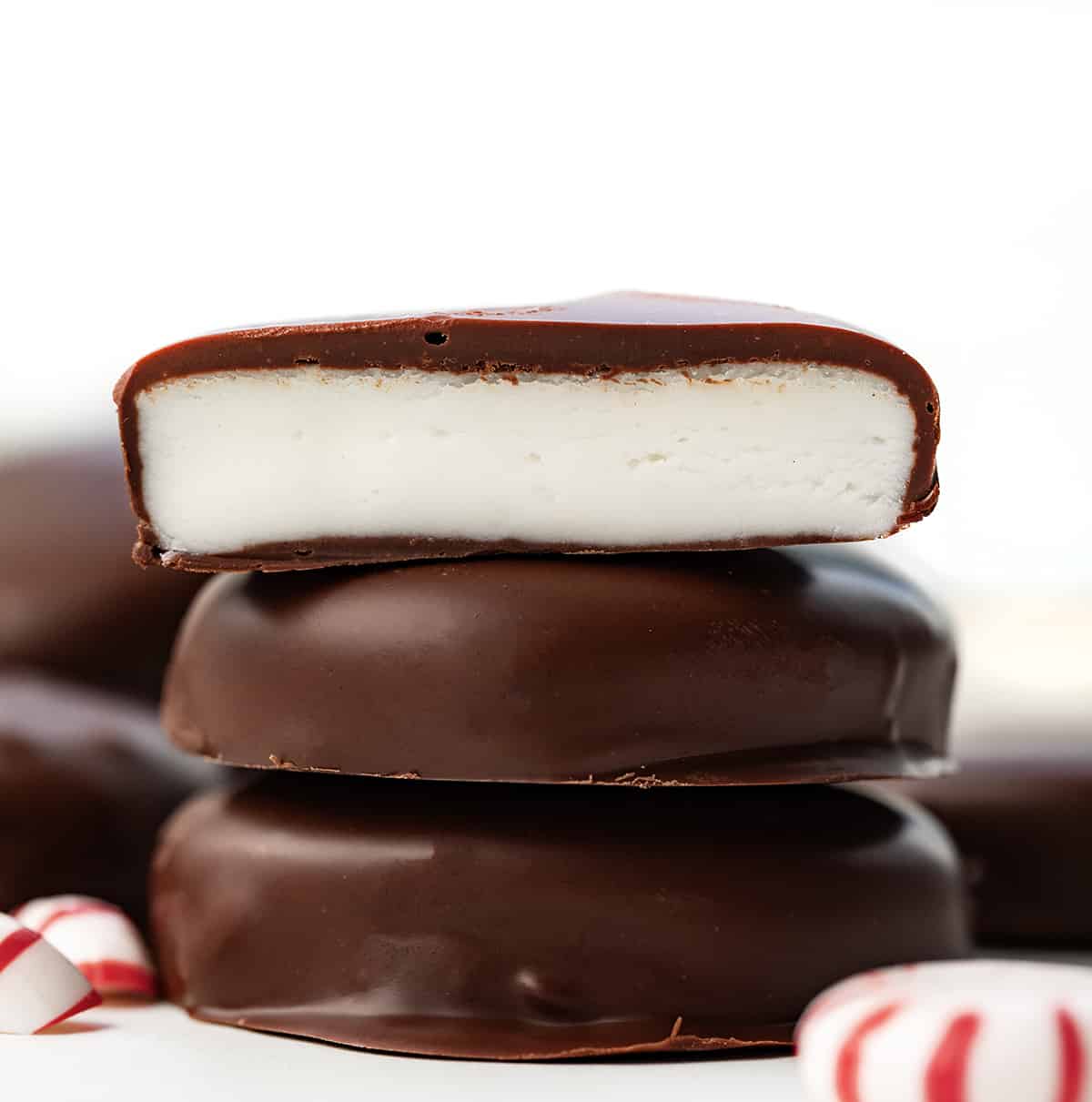 Stack of Homemade Peppermint Patties with top patty halved showing inside.