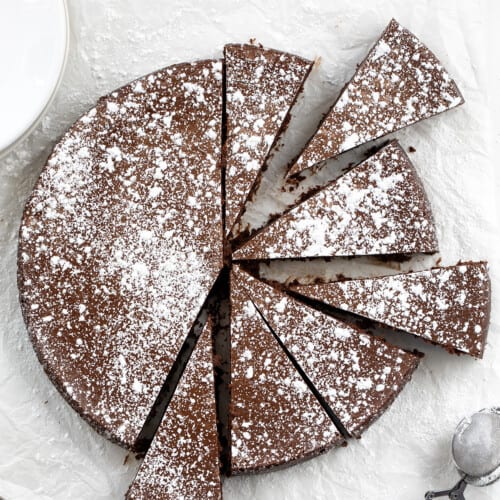 Flourless Chocolate Cake on a White Counter Cut into Pieces.