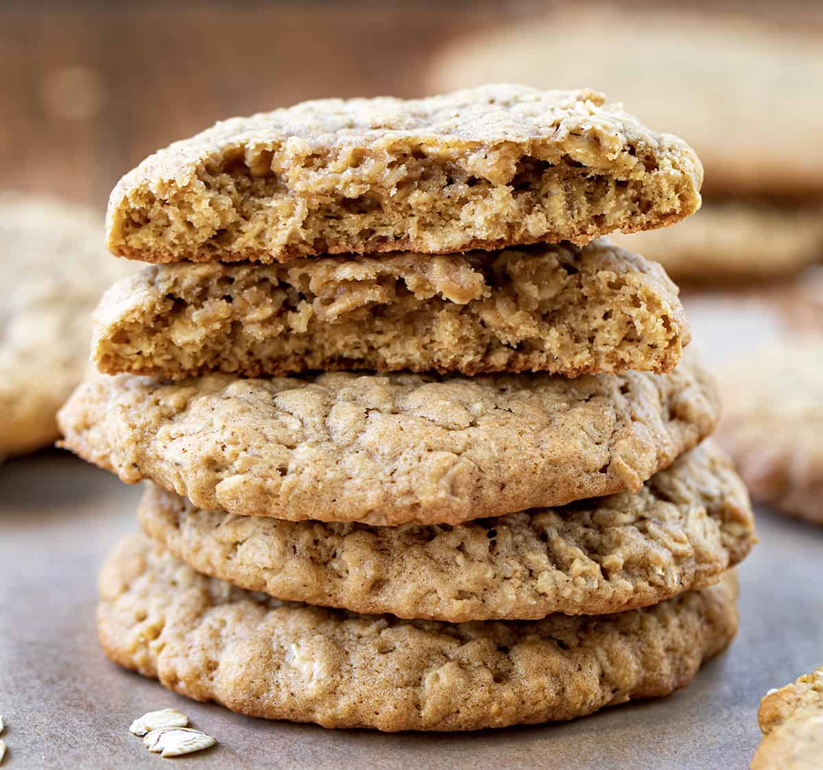 Stacked Oatmeal Cookies on a Wooden Cutting Board Surrounded by Cookies.