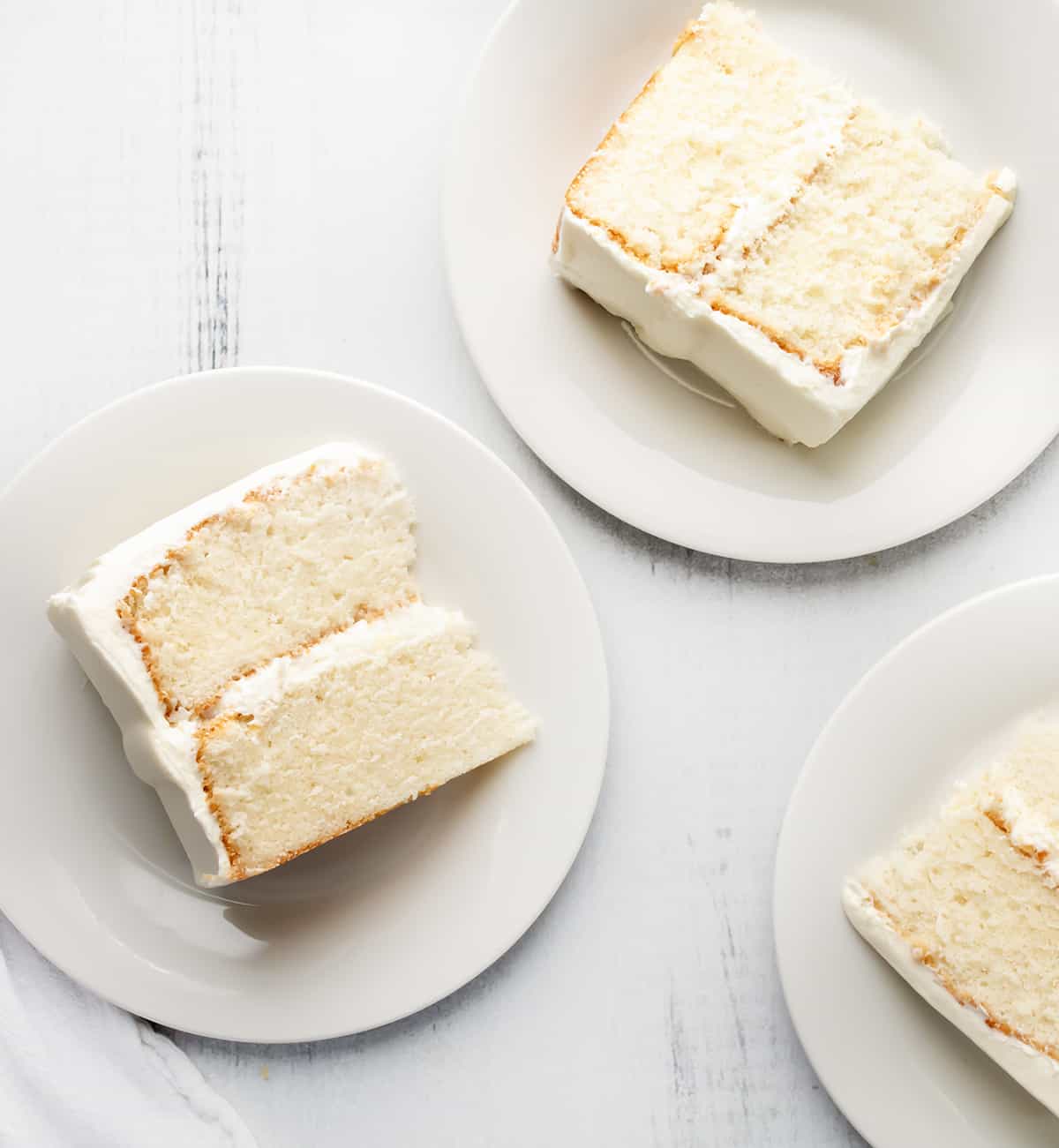 Pieces of White Cake on White Plates.