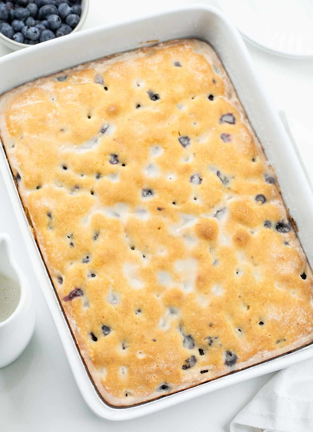 This Blueberry Breakfast Cake is tender, moist, and bursting with sweet, juicy blueberries in every bite! Blueberry Breakfast Cake in a white pan on a white table.