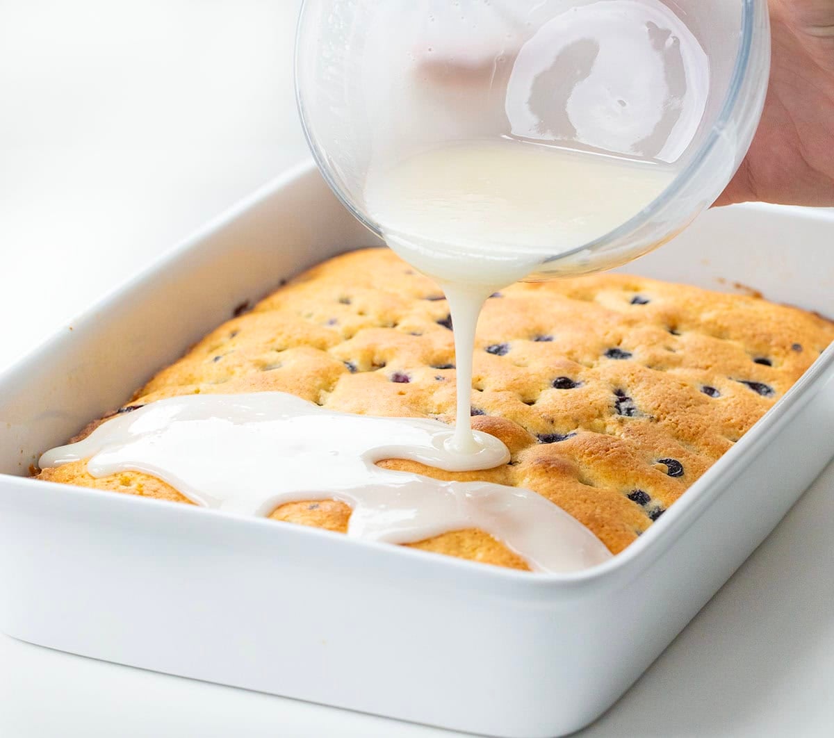 This Blueberry Breakfast Cake is tender, moist, and bursting with sweet, juicy blueberries in every bite! Drizzling glaze over Blueberry Breakfast Cake.