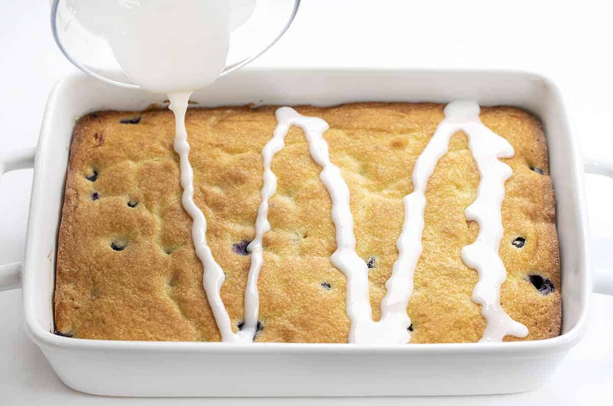 Pouring Sweet Glaze over a Blueberry Breakfast Cake. 