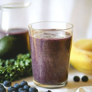 Glass of Blueberry Avocado Smoothie with bananas, blueberries, and avocado.