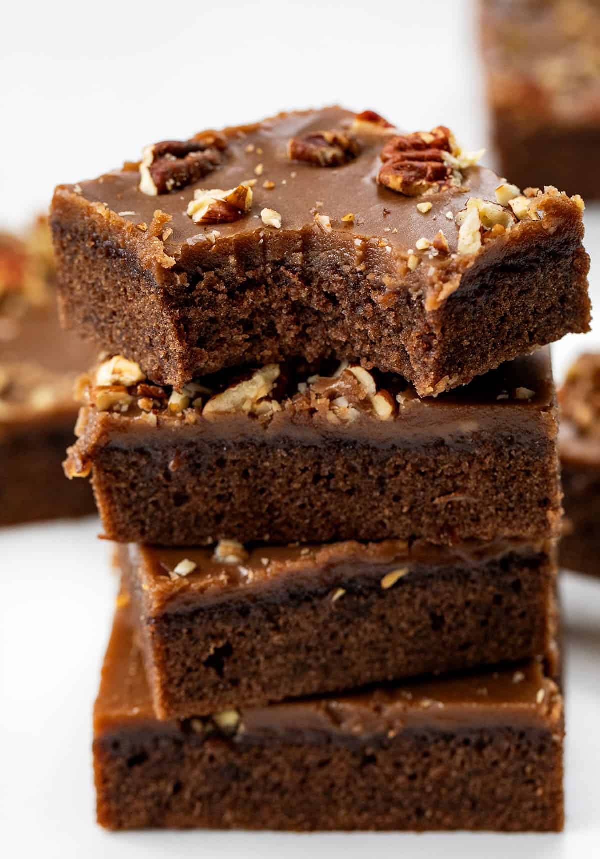 Stack of Texas Brownie Cake bars with the top bar with a bite taken out of it.