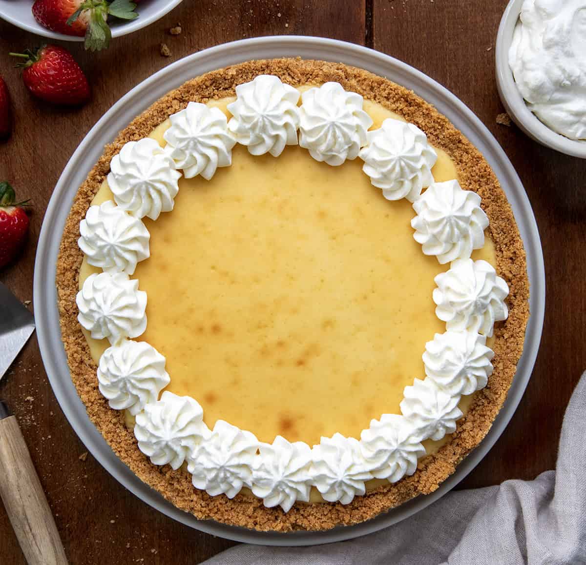 This Classic Cheesecake with Double Crust is perfect for anyone who loves a thick, buttery graham cracker base with a rich, creamy filling! Whole Classic Cheesecake With Double Crust on a wooden table from overhead.