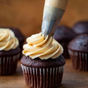 Piping Peanut Butter Frosting onto a chocolate cupcake.