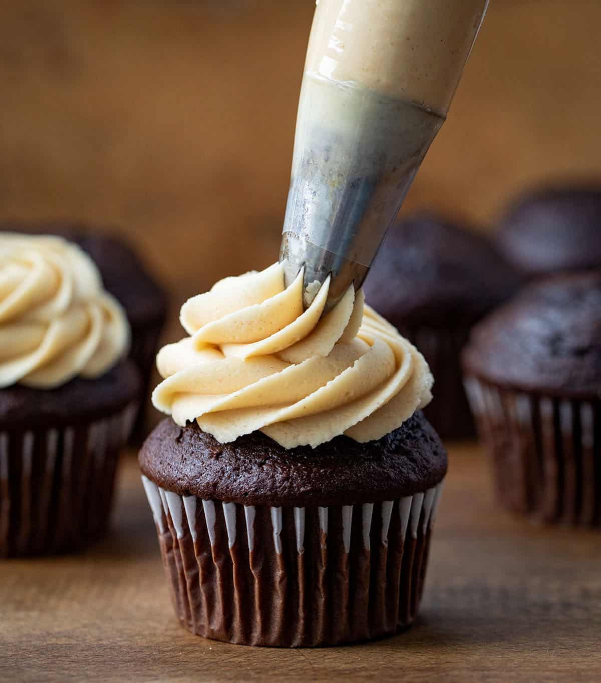 Piping Peanut Butter Frosting onto a chocolate cupcake.