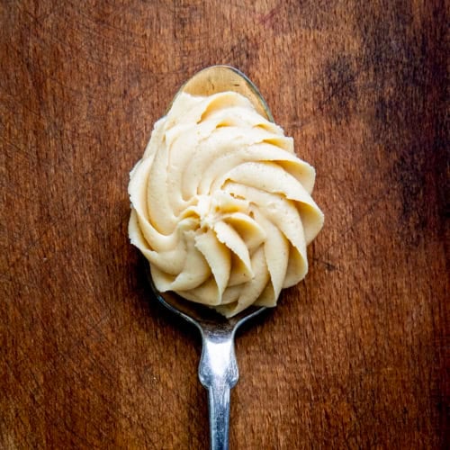 Spoonful of Peanut Butter Frosting on a wooden table very close up.