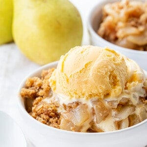 Bowl of Gingered Pear Crisp with Ice Cream and Pear in the Background. Dessert, Baking, Crisp, Best Crisp Recipes, Pear Crisp, Easy Pear Crisp, Holiday Desserts, Holiday Recipes, Old Fashioned Recipes, Historic Recipes, Grandma's Recipes, i am baker, iambaker