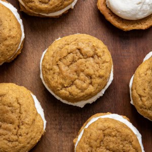 Pumpkin Sandwich Cookies with Brown Butter Buttercream on a wooden table from overhead.