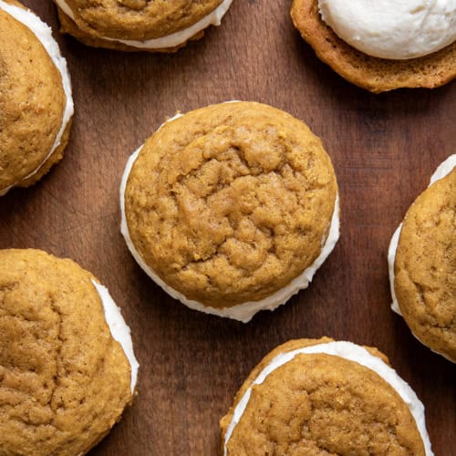 Pumpkin Sandwich Cookies with Brown Butter Buttercream on a wooden table from overhead.