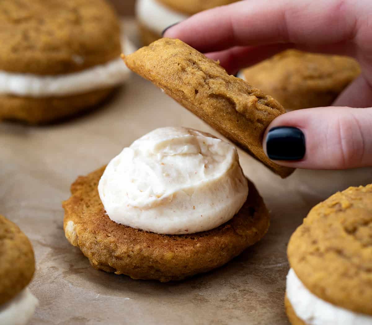 Putting the top of he cookie onto a Pumpkin Sandwich Cookies with Brown Butter Buttercream.