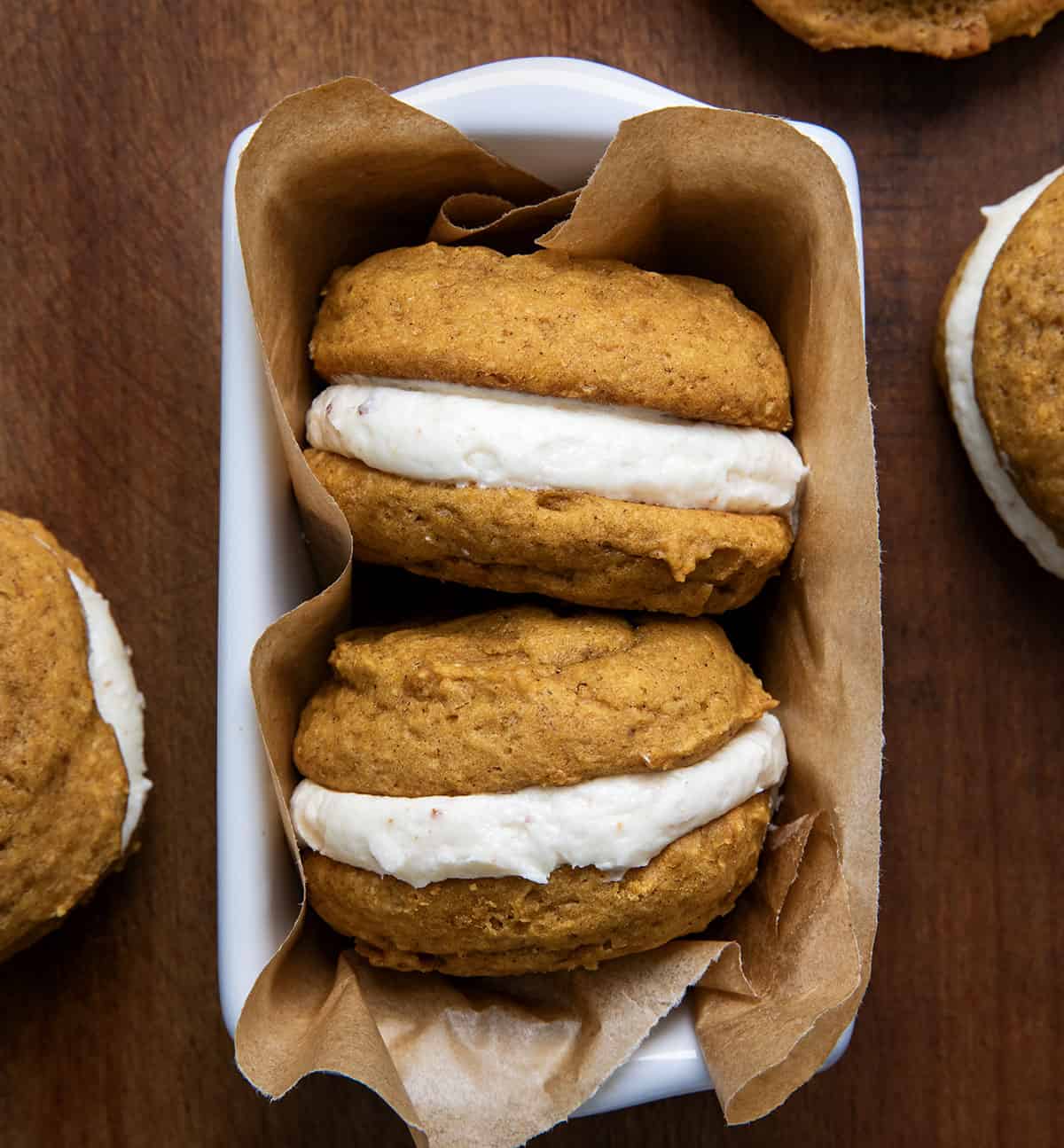 Two Pumpkin Sandwich Cookies with Brown Butter Buttercream in a container from overhead.