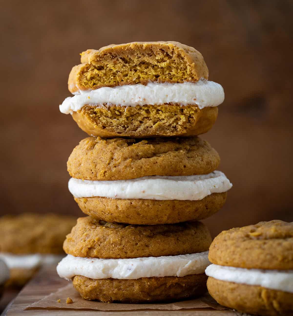 Stack of Pumpkin Sandwich Cookies with Brown Butter Buttercream with the top cookie cut in half showing inside texture.