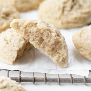 Cinnamon Butter Cookies on a Cooling Rack with Parchment and a Cookie Halved Showing Inside Texture.