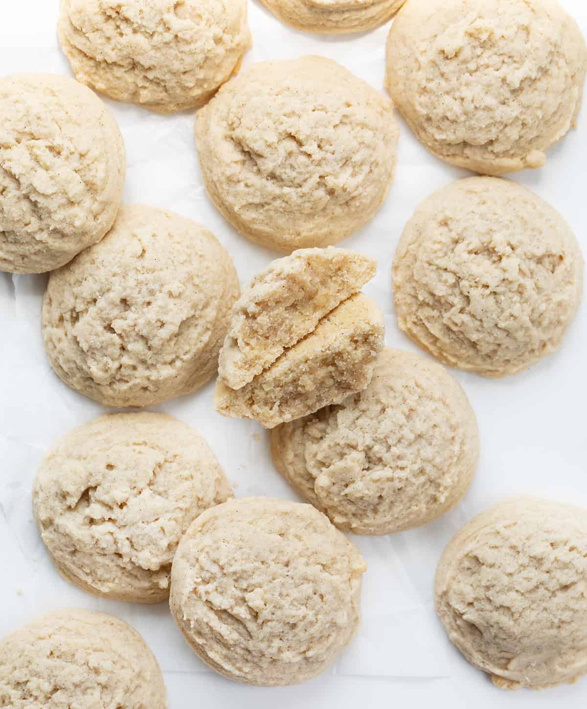 Cinnamon Butter Cookies on a White Counter With One Cookie Broken in Half.