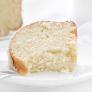 Piece of Vanilla Bundt Cake Laying on a Plate with a Bite Removed and the Fork Resting on the White Plate.