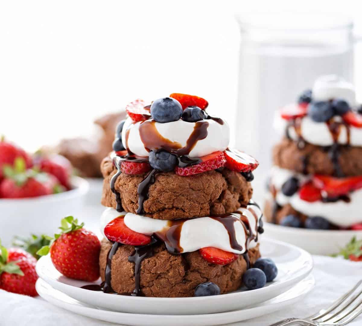 Chocolate Strawberry Shortcakes on white plates pm a white table.