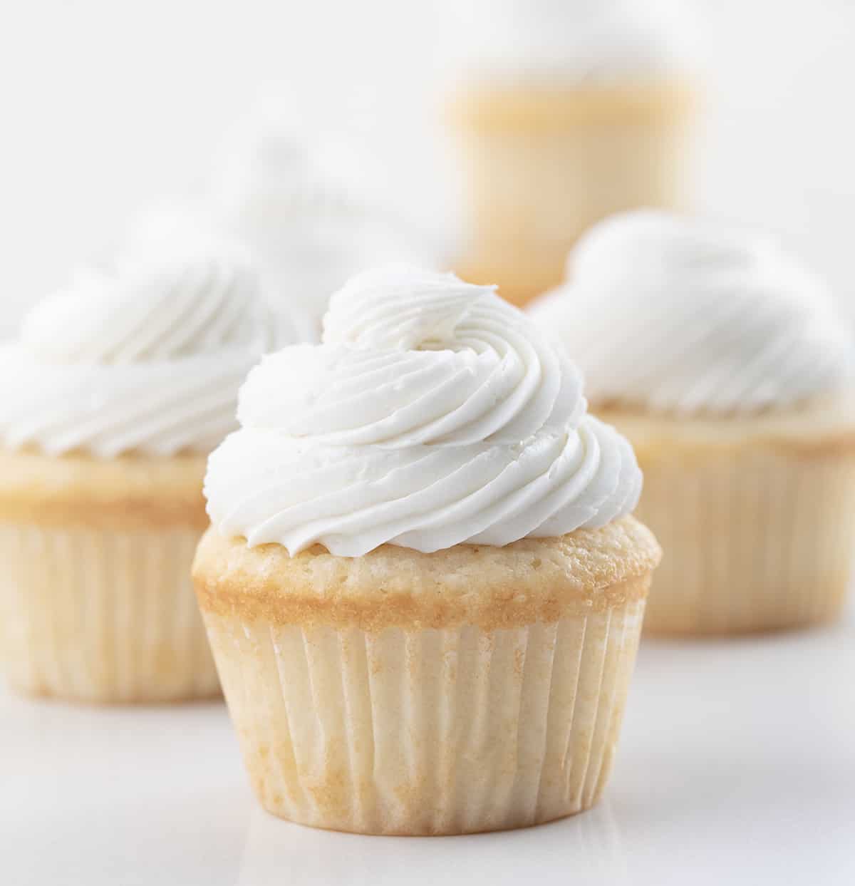 White Cupcakes with Vanilla Frosting on a White Counter.