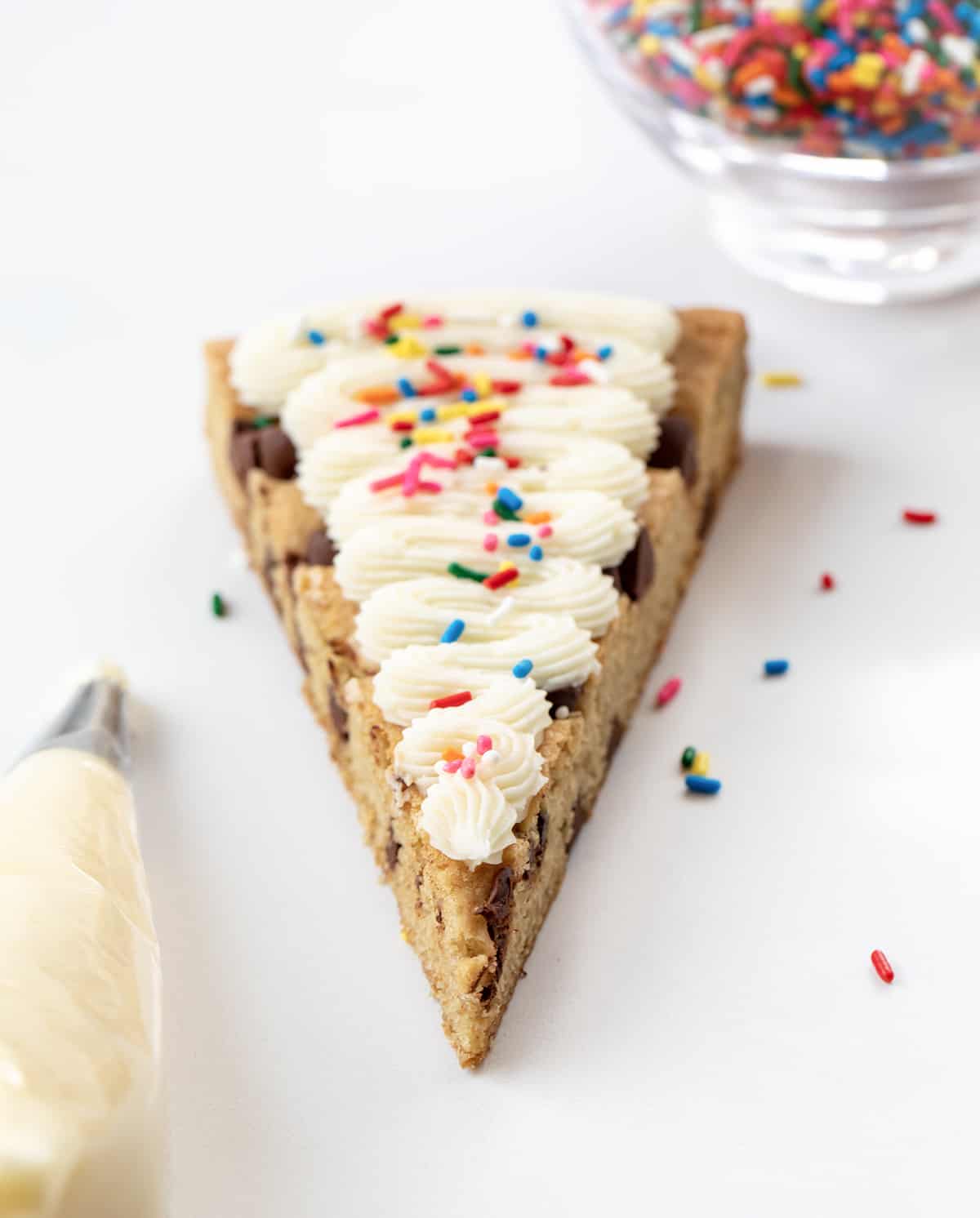 One Piece of Cookie Cake for a Crowd with Vanilla Frosting, Sprinkles, and Piping Bag.