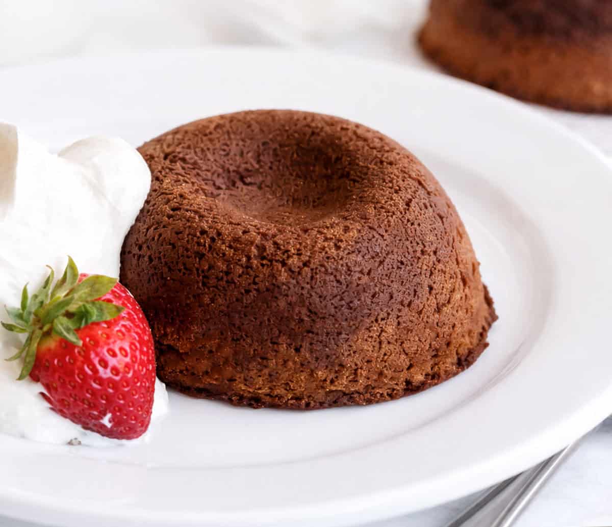 Molten Lava Cake on a white plate with a strawberry.
