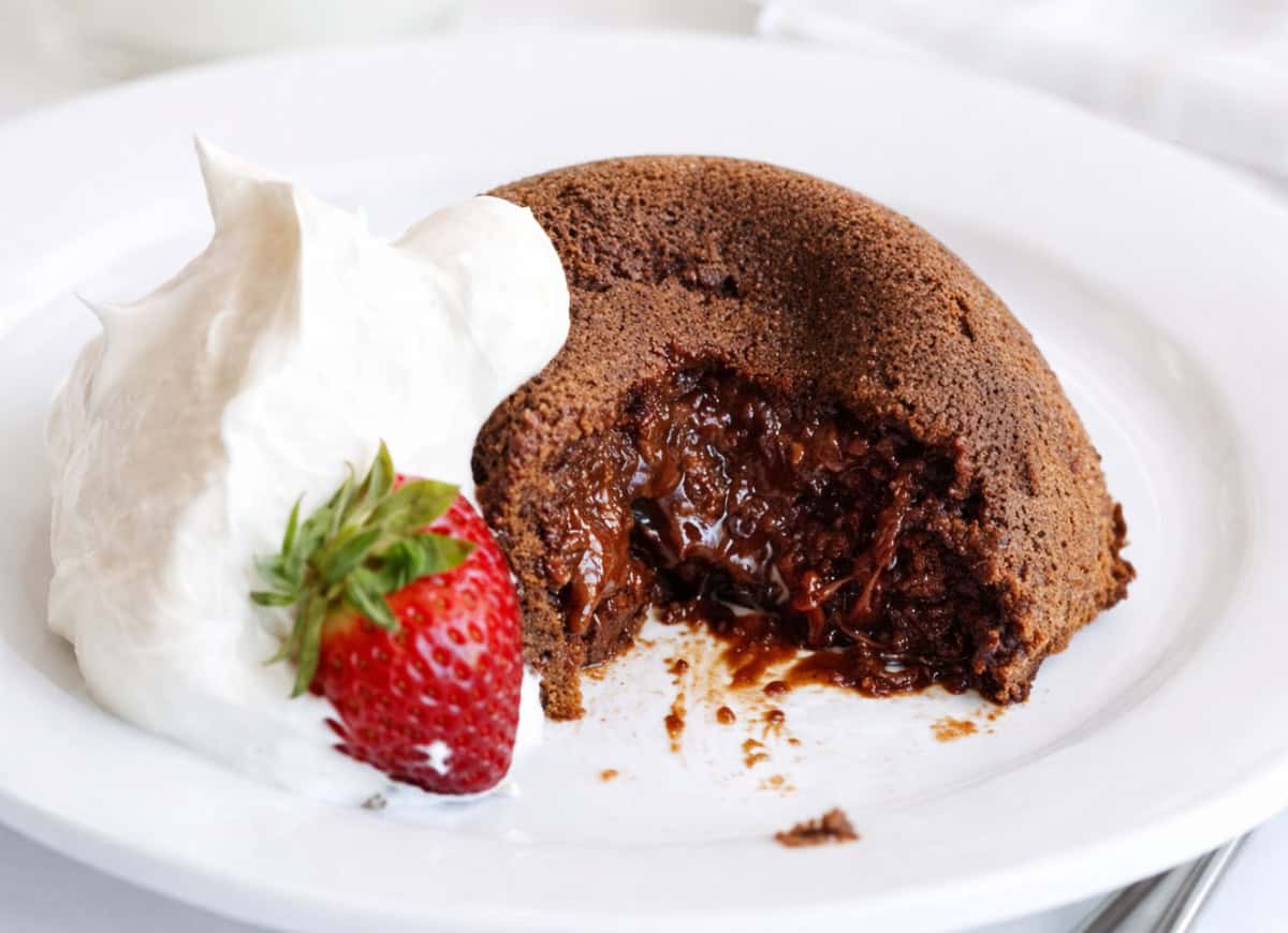 Molten Lava Cake on a white plate with some whipped cream and a strawberry!