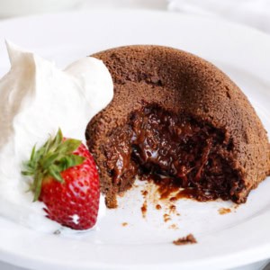 Molten Lava Cake on a white plate with some whipped cream and a strawberry!