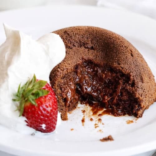 Molten Lava Cake on a white plate with some whipped cream and a strawberry!