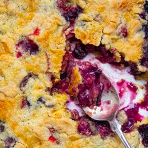 CLose up of fruit cobbler in a pan with spoon showing texture under the crust.