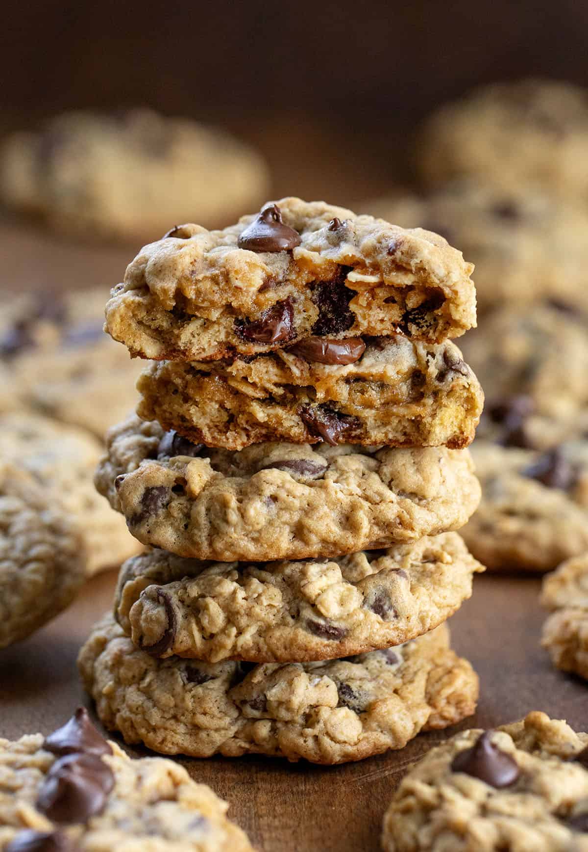 Stack of Oatmeal Chocolate Chip Cookies with the top cookie broken in half on a wooden table.