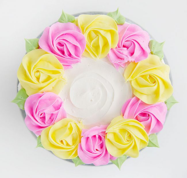 Create simple rustic lines in buttercream and then adorn with pink and yellow buttercream rosettes!