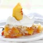 The perfect slice of peach pie with whipped cream and peach garnish!