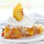 The perfect slice of peach pie with whipped cream and peach garnish!