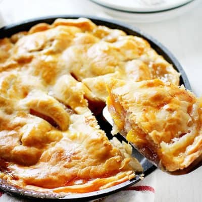 A perfectly baked and delicious peach pie with a piece headed for my plate!