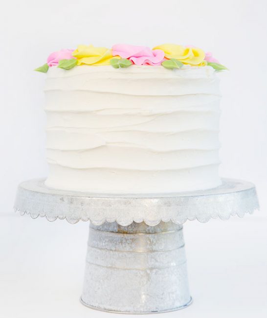 Creating rustic lines on the sides of this cake make for a pretty compostion when adding simple pink and yellow rosettes to the top.