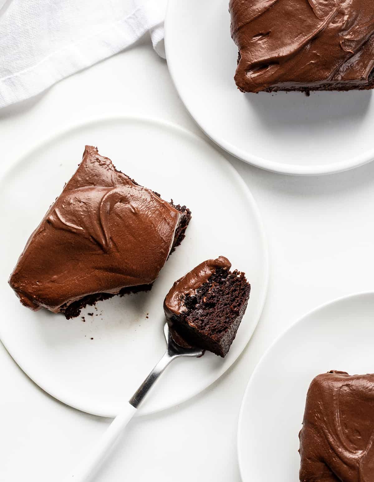 Pieces of Double Fudge Cake on White Plates with One Piece Next to a Fork with Some Cake on It.