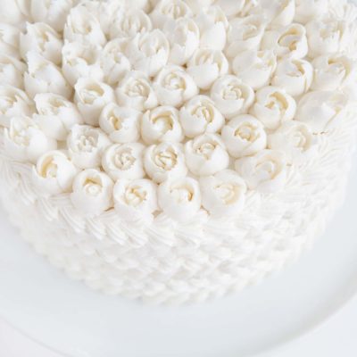 Cake covered in white butercream with Russian tip roses on top!