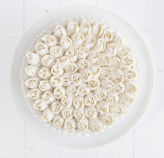 Overhead view of a cake covered in Russian tip roses with whipped vanilla buttercream.