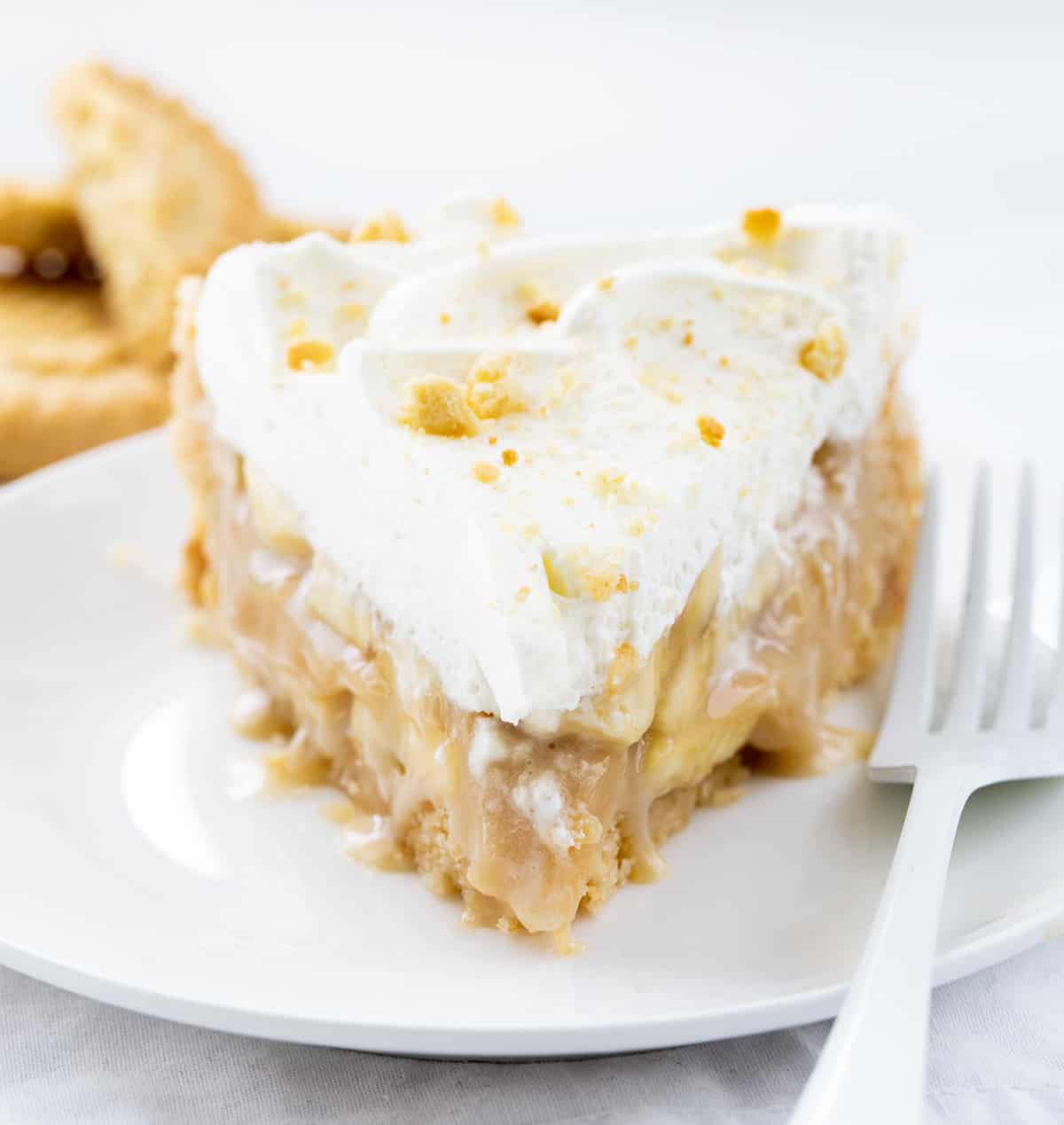 Piece of Banoffee Pie on a White Plate on a White Background.