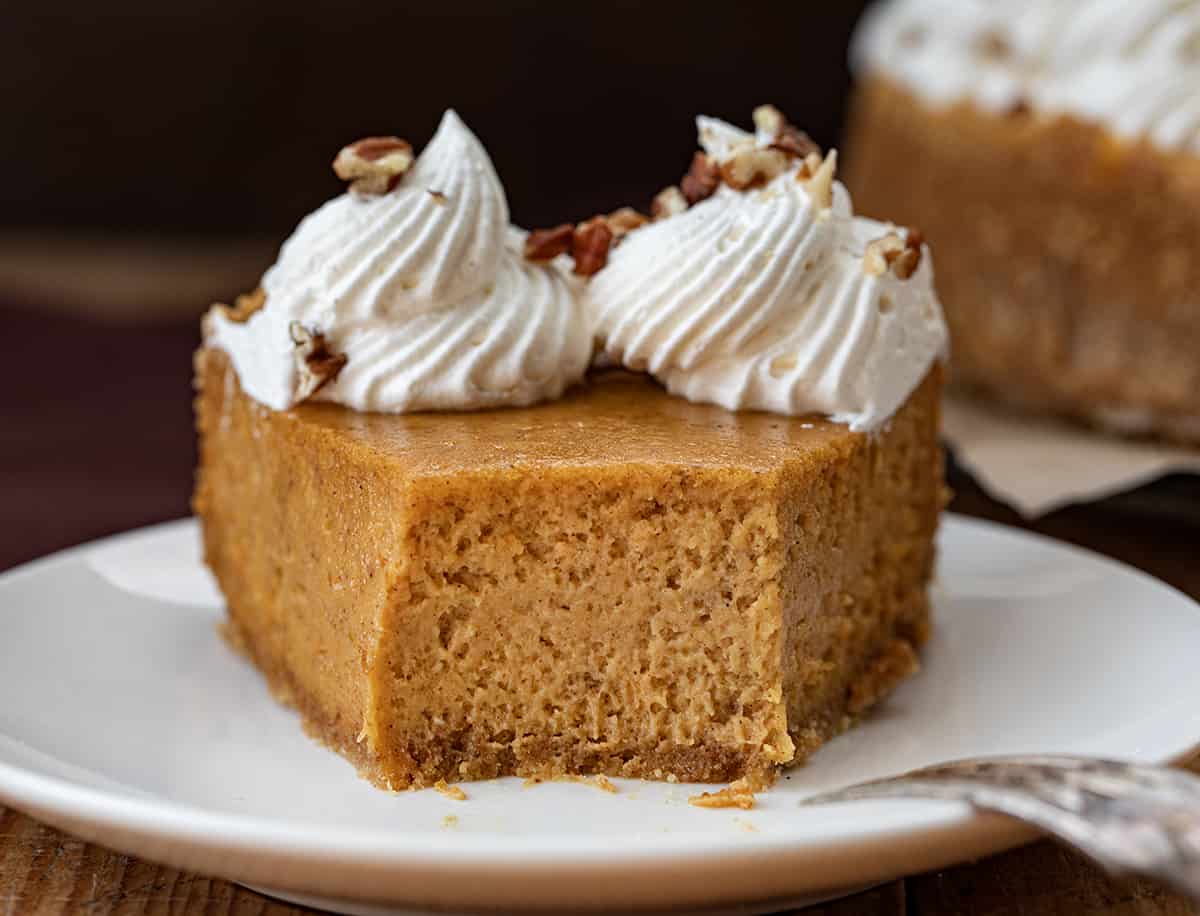 Piece of Pumpkin Cheesecake on a Plate with a Bite Removed and Fork Resting on Plate.