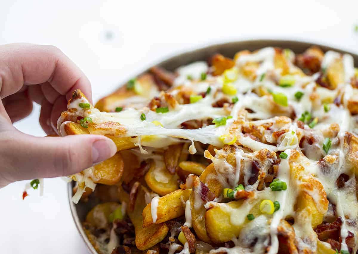 Loaded Cheese Fries Being Pulled with Hand Showing Stretchy Cheese