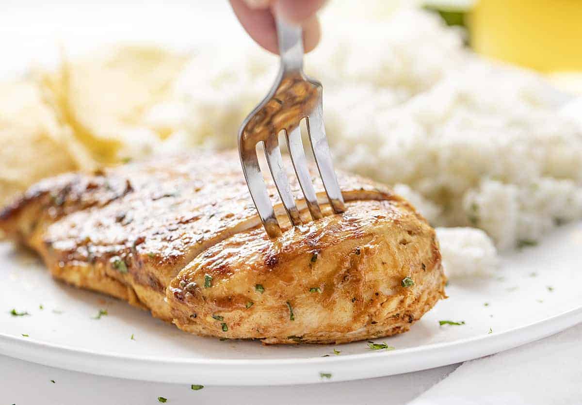 Fork Cutting a Piece of Cilantro Lime Chicken on White Plate