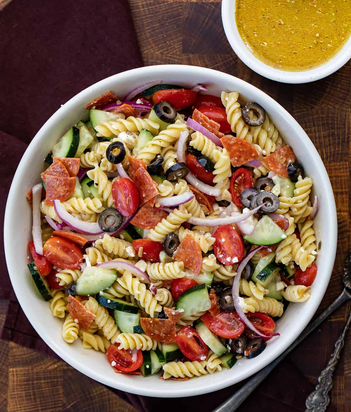 Bowl of Greek Pasta Salad with Dressing off to the Side.