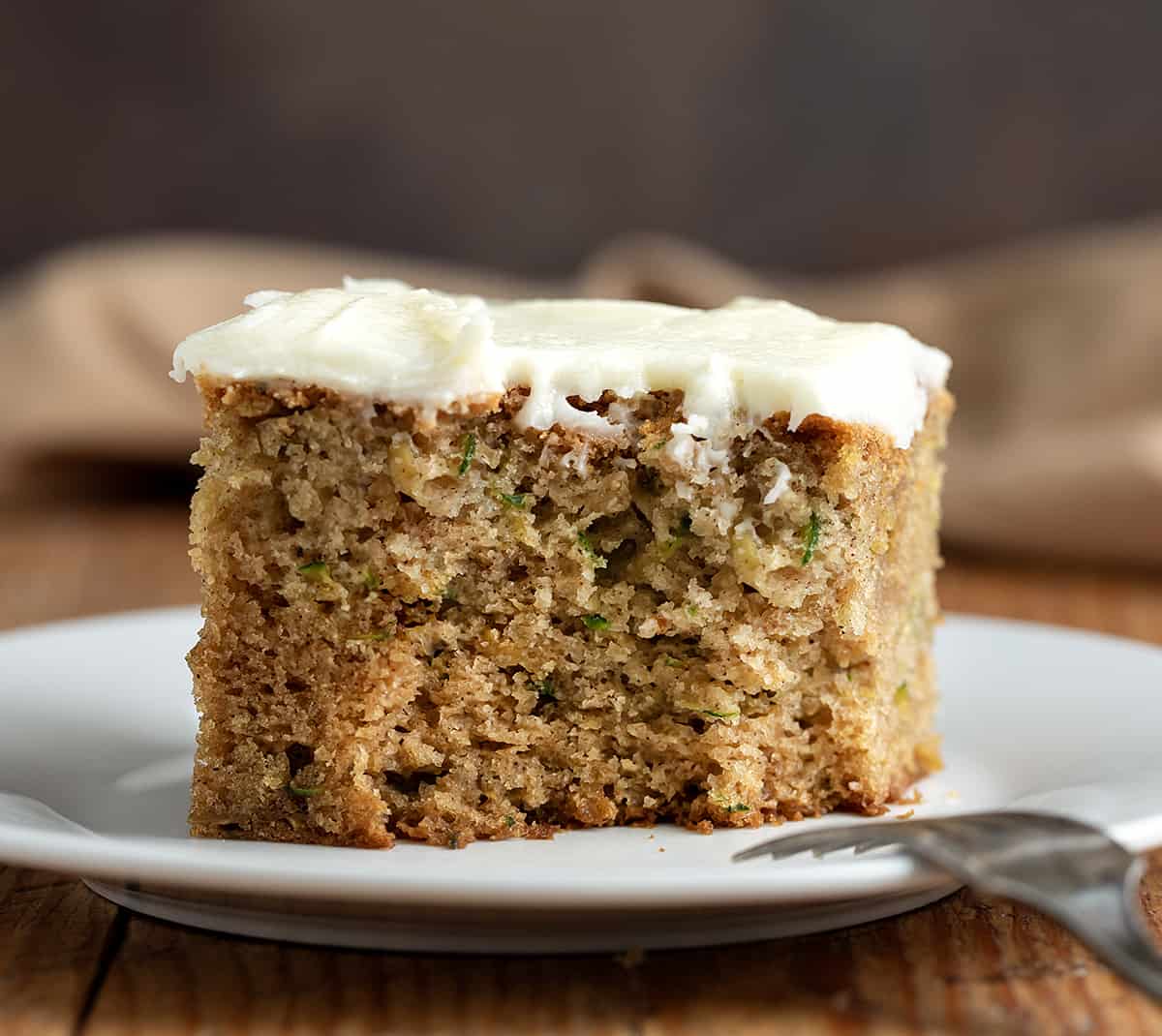 Piece of Zucchini Cake on a Plate with A bite Removed.