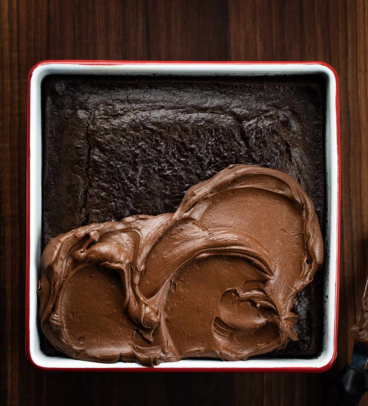 Chocolate Brownie Frosting Being Spread Over a Chocolate Mayo Cake.