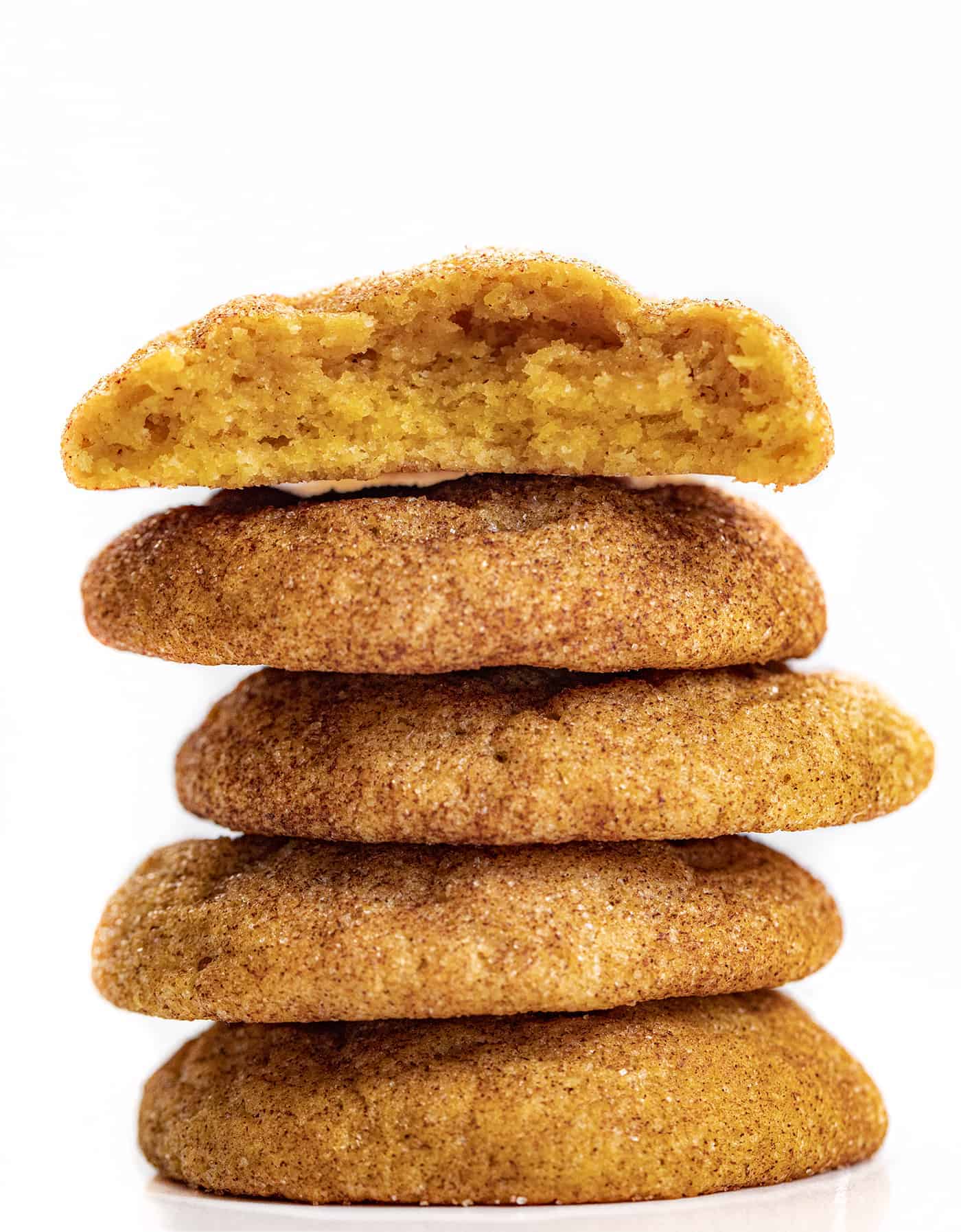 Stacked Pumpkin Snickerdoodle Cookies with One Broken in Half on Top