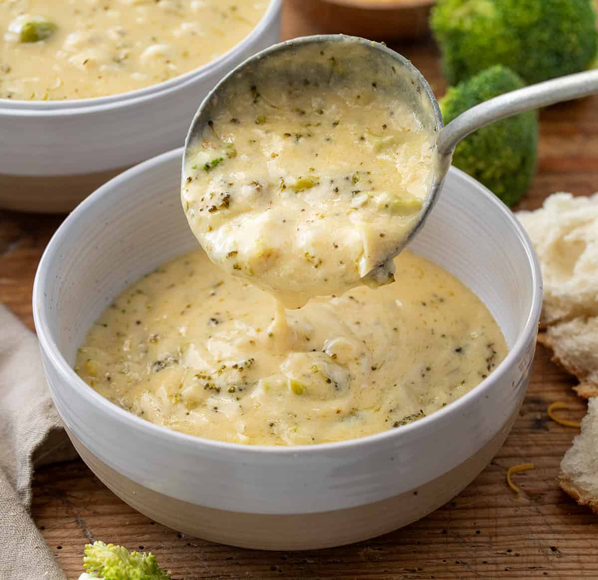 Scooping Roasted Broccoli and Cheese Soup into a Bowl with a Silver Ladle.